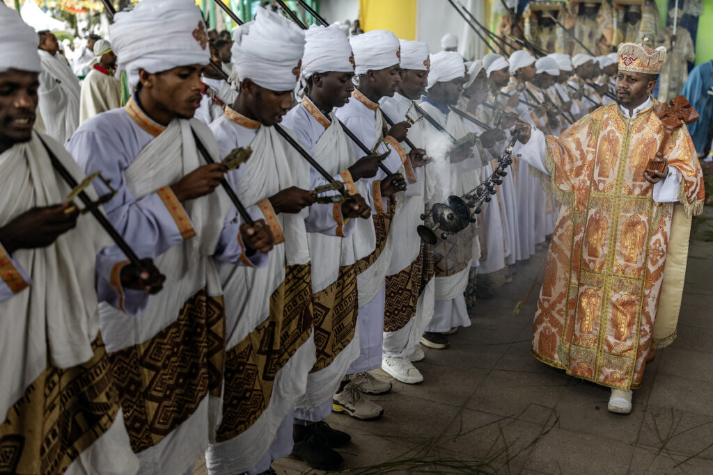 An Ethiopian Orthodox priest swings a censer as deacons sing religious songs and prayers during a New Year church celebration at Entoto St. Raguel Church in Addis Ababa, on September 11, 2025. Ethiopia marks the New Year, Enkutatash in Amharic, on September 11, celebrating the end of the rainy season and the start of the Ethiopian calendar year 2018, which runs about seven to eight years behind the Gregorian calendar. (Photo by Luis TATO / AFP)